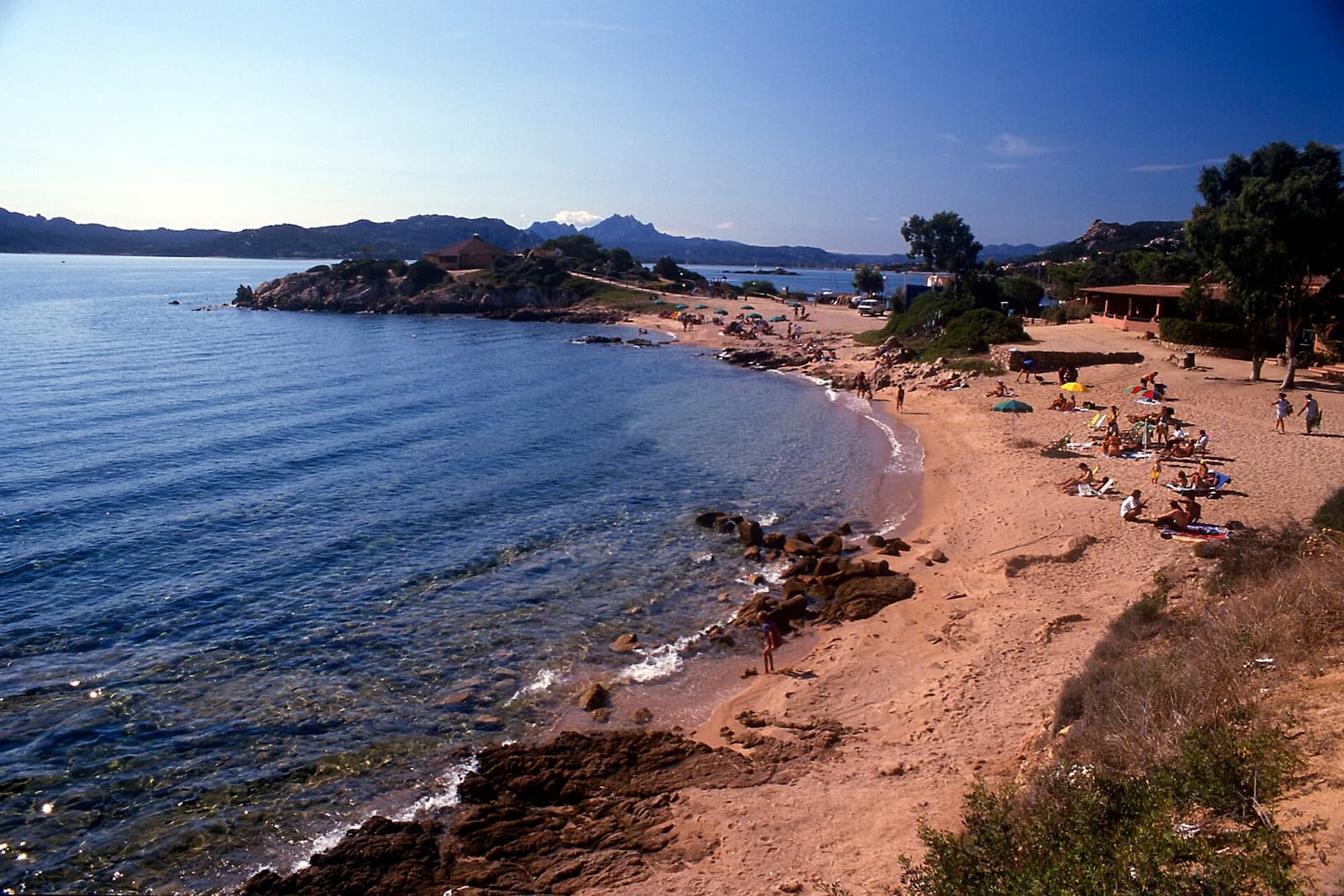 Spiaggia e scogli sulla costa del golfo di Arzachena presso il campeggio Isuledda, con i monti sullo sfondo