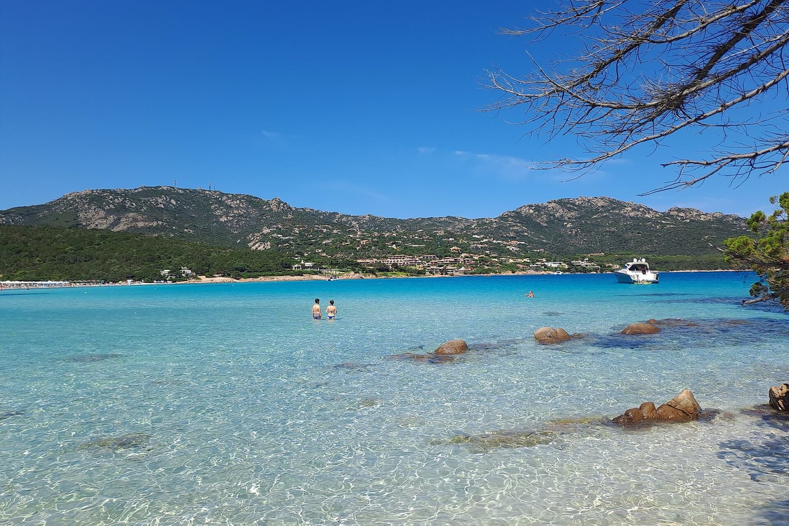 Acqua cristallina e scogli di granito nel golfo del Pevero, con le colline verdi alle spalle della costa