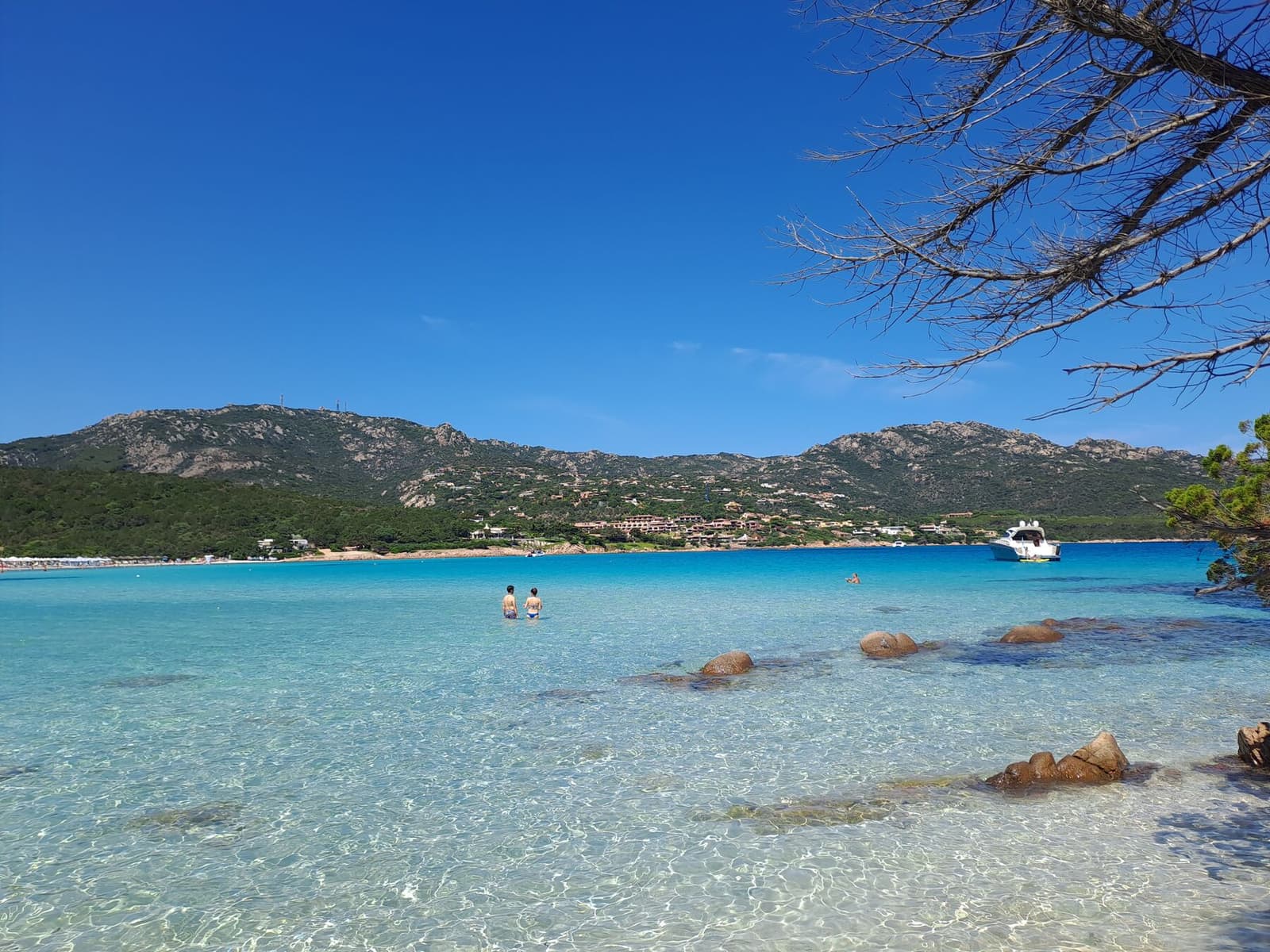 La spiaggia del Pevero con l'acqua bassa e le case sulla collina