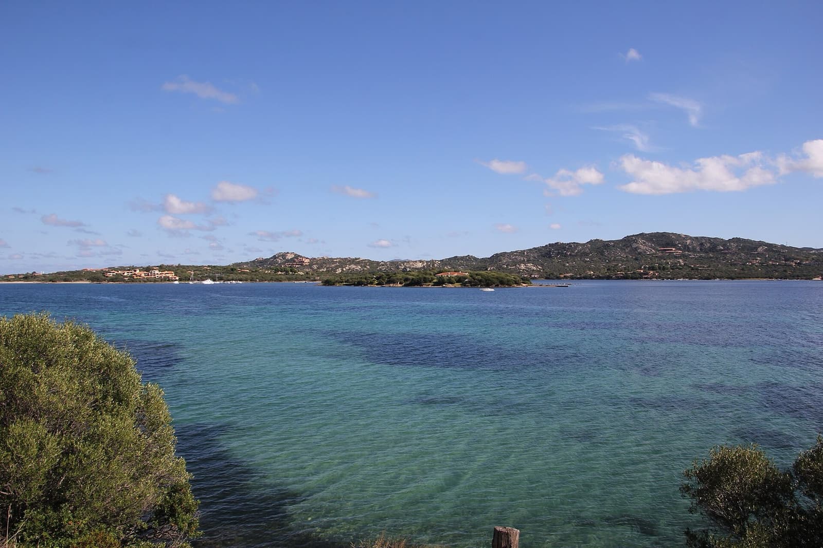 Acque turchesi del golfo di Cugnana tra la macchia mediterranea, con le colline sulla sponda opposta